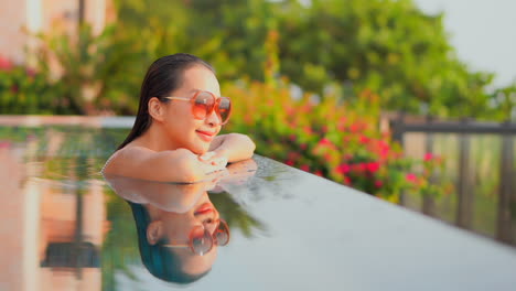 Happy-satisfied-young-asian-woman-enjoying-in-serenity-of-swimming-pool-tropical-weather-on-holiday-vacation,-slow-motion-close-up