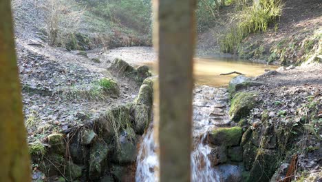 Kleiner-Kaskadierender-Felsenwasserfall-Kupferfarbener-Pool,-Der-Hinter-Metallgeländern-Fließt,-Nahaufnahme-Dolly-Rechts