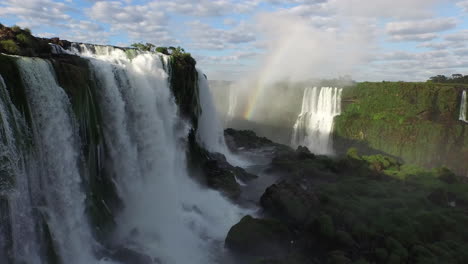 Aerial---A-rainbow-in-Iguazu-Falls,-Misiones,-Argentina,-wide-lowering-shot