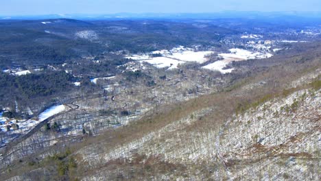 Aerial-drone-video-footage-of-a-snowy-mountain-valley-during-early-spring-with-sunny-blue-skies