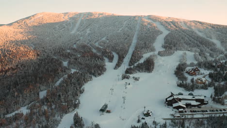Wide-aerial-view-of-Saddleback-Ski-Area-in-Rangeley,-Maine-during-golden-hour-sunset