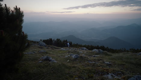 A-shot-of-valley-from-the-mountain-Peca,-Hiker-walkih-past-in-the-distance-with-hiking-poles-in-early-morning-before-sunrise