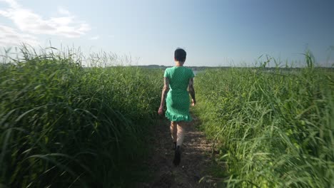Gimbal-view-of-woman-walking-on-a-path-through-long-grass-beside-the-ocean