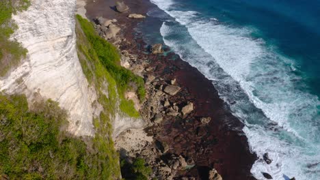 Aerial-tilt-down-of-the-rocky-beach-next-to-epic-Karong-Boma-cliff