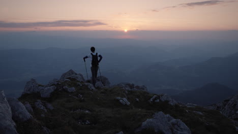 Camera-tracking-a-young-hiker-who-has-topped-at-the-edhge-of-a-mountain-ridge-to-admire-a-beautiful-sunrise
