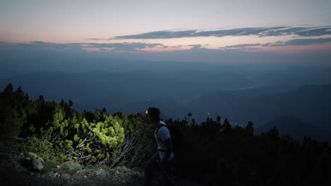 Hiker-walking-past-the-camera-with-the-hiking-polesa-and-headtorch-looking-at-hte-valley-and-direction-of-where-the-sun-will-rise