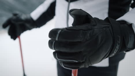 Close-up-shot-of-a-woman-in-skiing-gear-and-gloves-on-her-hands-takes-in-hands-skiing-poles