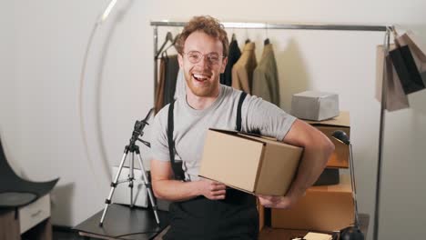 Cute-curly-man-holding-a-cardboard-box-smiling