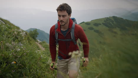 Hiker-in-red-jacket-and-a-backpack-walking-up-a-hill-on-a-narrow-rocky-path
