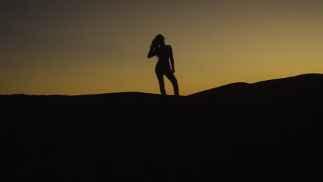 Silhouette-Einer-Frau,-Die-Während-Eines-Atemberaubenden-Sonnenuntergangs-Auf-Der-Spitze-Einer-Sanddüne-In-Der-Wüste-Tanzt