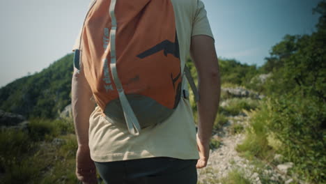 Camera-tracking-a-hiker-with-an-orange-backpack-going-from-low-perspective-to-the-top-perspective