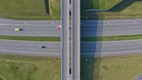 Traffic-flow-on-highway-with-overpass,-green-landscape-surrounds-asphalt