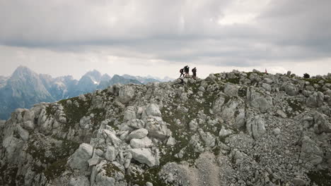 Drone-shot-of-mountain-Rombon,-a-group-of-hikers-walking-on-the-ridge-of-it-towards-the-top