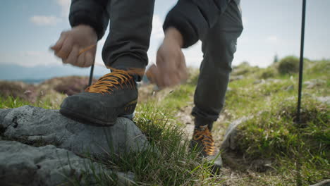 Close-up-shot-of-hikers-legs,-walking-towards-the-camera-stopping-putting-his-foot-on-the-rock-to-tie-his-laces