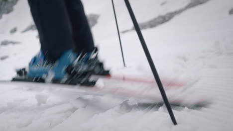 Close-camera-shot-of-a-woman-standing-on-snow-with-skis-and-ski-boots,-she-turns-the-skis-and-starts-to-ski-downhill