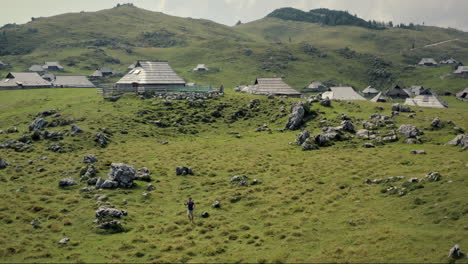 A-drone-shot-of-the-Velika-planina,-hiker-walking-across-the-green-meadow