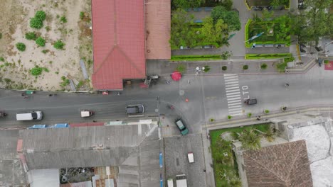 Top-down-aerial-footage-of-an-intersection-in-Panajachel,-Guatemala-with-cars-going-and-stopping-and-people-walking