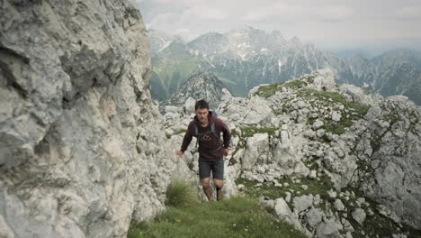 Camera-tracking-hiker-in-front-on-a-grenn-grassy-path-towards-the-top-of-mountain