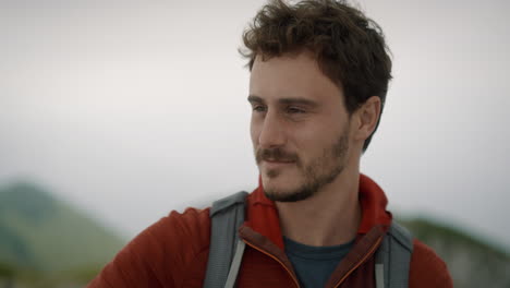 Close-up-of-a-young-hiker-with-a-backpack-and-a-red-jacket,-smiling-and-looking-into-the-distance