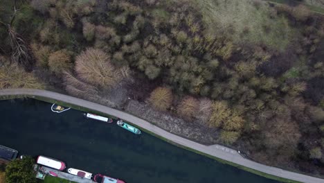 High-angle-top-down-shot-of-parking-ships-om-seaside-of-port-surrounded-by-rural-fields-and-trees-in-autumn