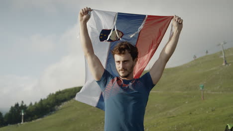 Man-holding-a-slovenian-flag-above-his-head-to-let-it-flutter-in-the-wind
