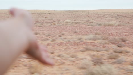 Hand-out-of-car-window,-dusty-outback-landscape
