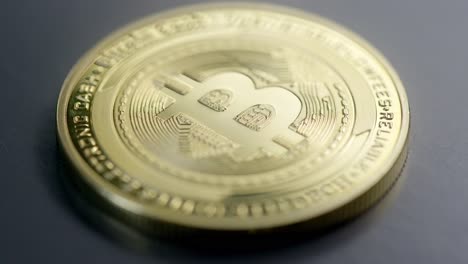 A-physical-golden-Bitcoin-coin-on-the-dark-table-with-a-rack-focus---macro-shot