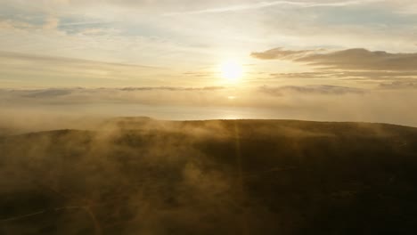 Atmospheric-nature-and-landscape-with-mist-and-fog-at-sunset,-drone-backwards