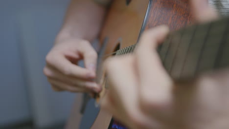 Slow-motion-close-up-footage-of-a-man's-fingers-picking-and-strumming-on-an-acoustic-guitar-with-a-rack-focus-up-the-neck-of-the-guitar