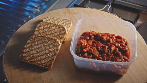 Spicy-Chicken-With-Beans-In-Food-Container-With-Slices-Of-Whole-Grain-Toast-On-The-Side