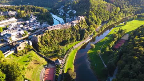 Aerial-shot-tilting-up-from-the-Meuse-River-in-Belgium's-countryside-to-reveal-the-Castle-of-Bouillon-on-the-high-ground