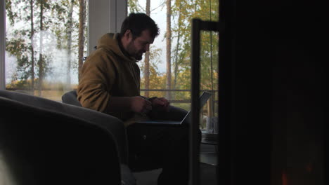 Side-view-of-man-sitting-comfortably-on-chair-working-remotely-from-home