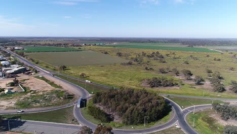 Trucks-and-cars-driving-on-the-road-through-green-fields,-sunny-day-with-blue-sky,-aerial-shot