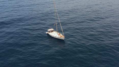 White-sail-boat-bobbing-on-blue-ocean-surface-in-Atlantic,-aerial