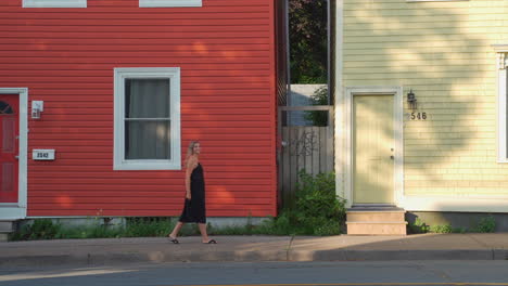 Close-shot-of-colourful-homes-with-woman-walking-in-front-of-in-the-morning-in-Halifax,-Nova-Scotia