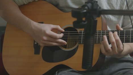 Close-up-of-fingers-picking-at-a-guitar-in-a-recording-studio