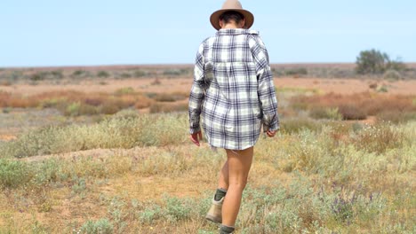 A-girl-walks-through-and-observes-a-desert-in-bloom,-following-outback-floods