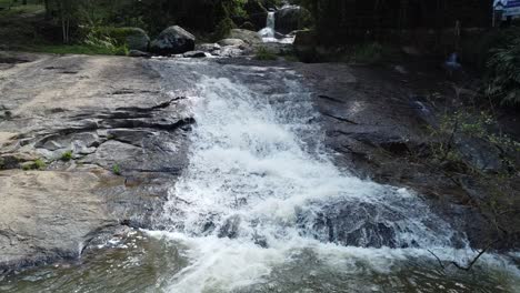 Drohnen-Kletter-Wasserfall,-Der-Ganz-In-Der-Nähe-Von-Wasser,-Natur-Und-Steinen-Filmt