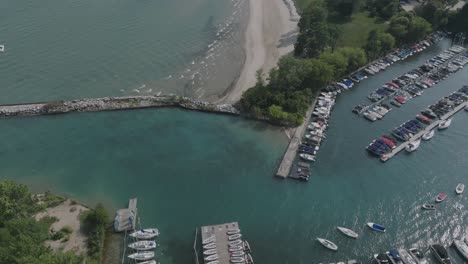 Luftaufnahmen-Der-Wellen-Des-Michigansees,-Die-Einen-Strand-Nördlich-Von-Chicago-Anspülen,-Mit-Booten,-Die-An-Einem-Jachthafen-Angedockt-Sind