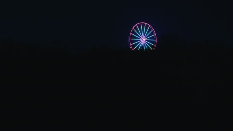 Ferris-wheel-illuminated-with-colorful-light-appearance-at-pitch-black-night,-Tallinn,-Estonia-T1-Mall
