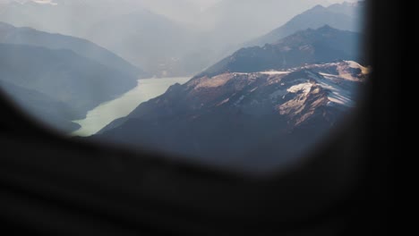 Slow-motion-shot-of-Mountains-and-lake-through-airplane-window-in-flight