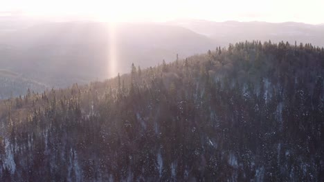 Sunrise-aerial-flight-over-boreal-forest-and-mountains-through-active-snowstorm-in-Quebec-Canada