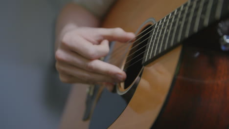 Slow-motion-close-up-footage-of-a-man's-fingers-picking-and-strumming-on-an-acoustic-guitar