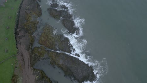 Top-down-aerial-view-of-waves-crashing-along-Ireland's-rocky-shore