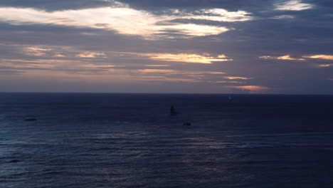 Silhouette-of-Boats-on-Ocean-At-Sunset,-Colorful-Clouds-at-Horizon-Line,-Hawaii,-Wide-Shot
