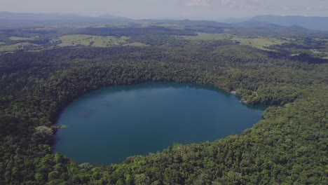 Volcanic-Lake-Eacham-With-Tropical-Vegetation-In-Atherton-Tableland,-Queensland,-Australia---aerial-drone-shot