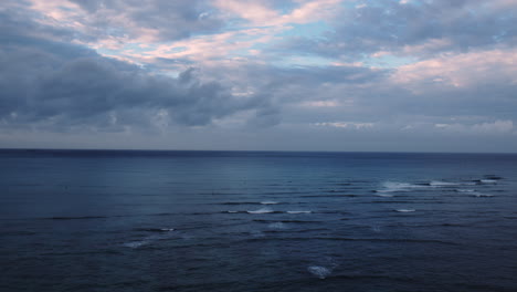 Dramatic-pink-clouds-over-calm-ocean-waves,-sunrise,-Waikiki,-Hawaii,-Aerial,-slow-motion