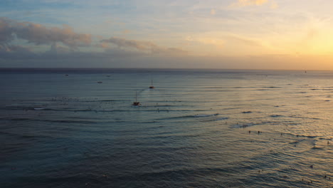 Two-Catamarans-Sail-Through-Tourists-Towards-Brilliant-colorful-Horizon,-Sunset,-Hawaii,-Aerial