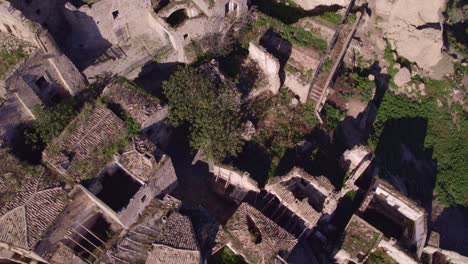 Craco-ghost-town-reclaimed-by-green-vegetation-in-Italy,-drone-shot