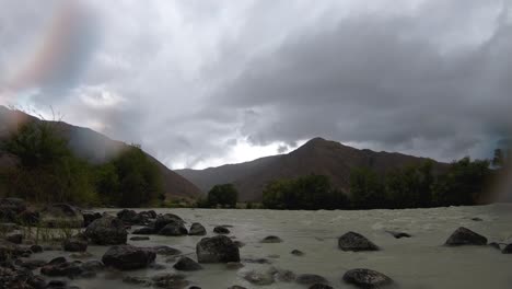 Timelapse-of-storm-over-mountains,-dirty-river-and-range